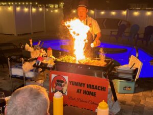 Chef plating hibachi steak and chicken for guests at an outdoor table
